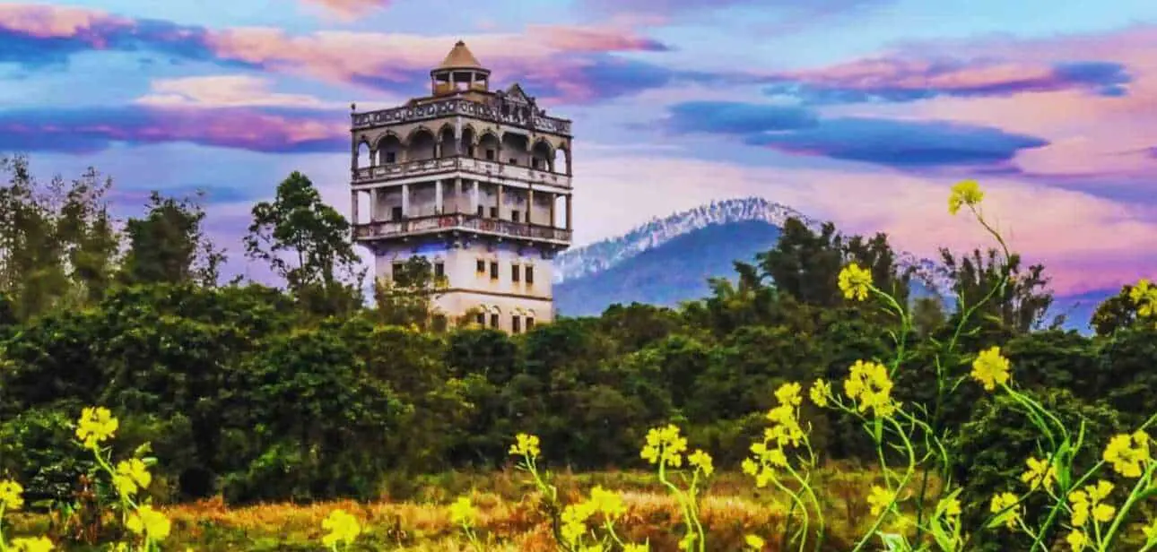 A Kaiping diaolou watchtower rising above village rooftops, a UNESCO World Heritage structure built with overseas remittance money bearing surname signatures