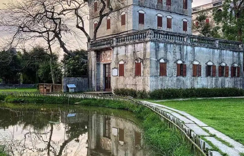 A historic Taishanese mansion reflecting in a pond at sunset in Zili Village, Kaiping — part of the Kaiping Diaolou and Villages UNESCO World Heritage Site, built with funds sent through the qiaopi remittance system.