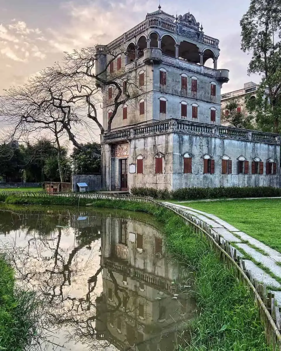 A historic Taishanese mansion reflecting in a pond at sunset in Zili Village, Kaiping — part of the Kaiping Diaolou and Villages UNESCO World Heritage Site, built with funds sent through the qiaopi remittance system.