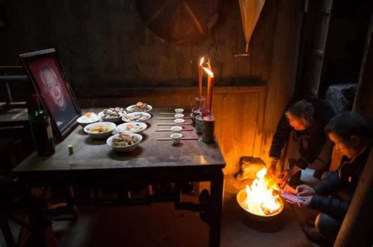 An ancestral offering table laid with food, tea cups, and candles — the eve-of-Qixi household rite of the qiaoxiang villages.