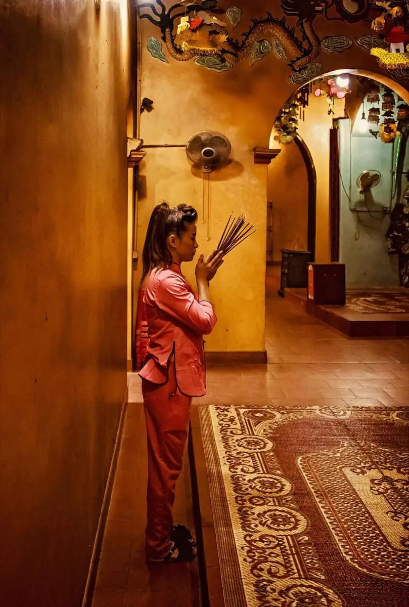 A woman offering incense in a Chinese ancestral hall, a contemporary ancestor-worship ritual