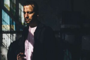 Stimmungsvolles Männerporträt mit Licht- und Schattenspiel in urbaner Umgebung.