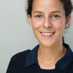 Bewerbungsfotos im Rostocker Fotostudio: Junge Frau mit dunklen Haaren lächelt freundlich vor einem neutralen, hellen Hintergrund. Ihr natürliches und professionelles Auftreten sorgt für einen sympathischen ersten Eindruck.