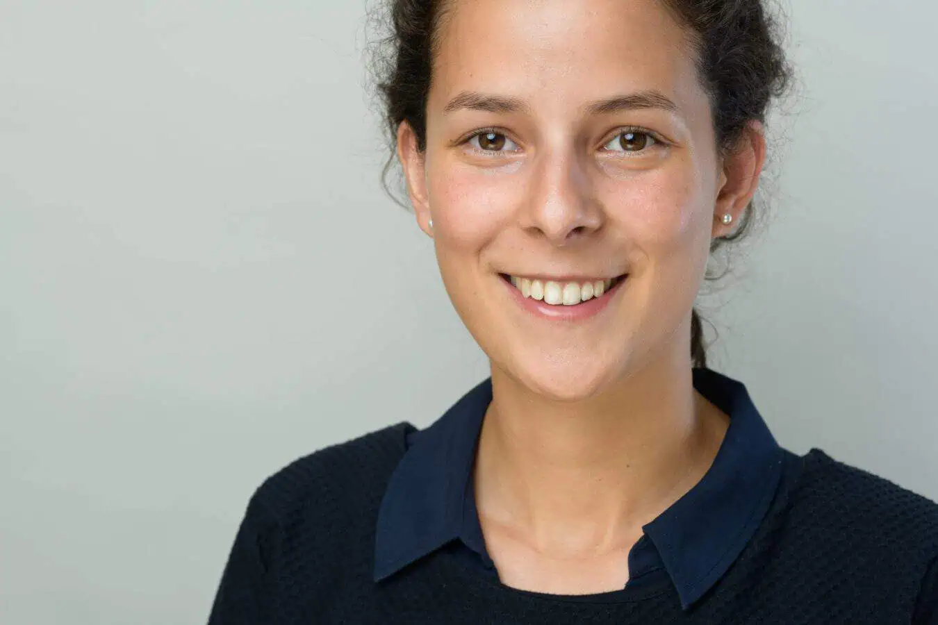 Modernes Bewerbungsfoto einer jungen Frau – authentisch, sympathisch und professionell Bewerbungsfotos im Rostocker Fotostudio: Junge Frau mit dunklen Haaren lächelt freundlich vor einem neutralen, hellen Hintergrund. Ihr natürliches und professionelles Auftreten sorgt für einen sympathischen ersten Eindruck.