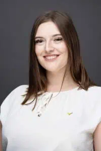 Bewerbungsfotos im Rostocker Fotostudio – Freundliches und professionelles Porträt einer jungen Frau mit weißer Bluse vor neutralem dunklen Hintergrund.