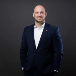 Bewerbungsfotos im Rostocker Fotostudio – Professionelles Business-Porträt eines selbstbewussten Mannes in einem dunkelblauen Anzug vor neutralem dunklem Hintergrund.