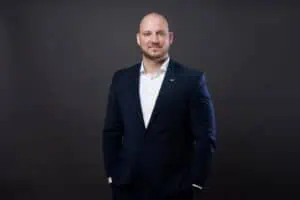 Bewerbungsfotos im Rostocker Fotostudio – Professionelles Business-Porträt eines selbstbewussten Mannes in einem dunkelblauen Anzug vor neutralem dunklem Hintergrund.