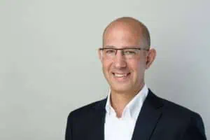 Bewerbungsfotos im Rostocker Fotostudio – Businessfoto eines Mitarbeiters von Transcom mit Brille, Glatze und dunklem Anzug vor hellem Hintergrund.