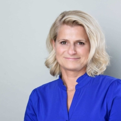 Bewerbungsfotos im Rostocker Fotostudio – Professionelles Bewerbungsbild einer selbstbewussten Frau mit blonden Haaren in einer blauen Bluse vor neutralem Hintergrund.