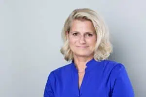 Bewerbungsfotos im Rostocker Fotostudio – Professionelles Bewerbungsbild einer selbstbewussten Frau mit blonden Haaren in einer blauen Bluse vor neutralem Hintergrund.