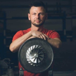 Martin Ehlert von der Firma Treckel lehnt an einem Turbolader und blickt in die Kamera – fotografiert vom Businessfotograf in Rostock.