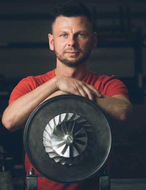 Porträt von Martin Ehlert – Präzision und Technik im Maschinenbau Martin Ehlert von der Firma Treckel lehnt an einem Turbolader und blickt in die Kamera – fotografiert vom Businessfotograf in Rostock.