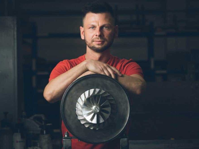 Porträt von Martin Ehlert – Präzision und Technik im Maschinenbau Martin Ehlert von der Firma Treckel lehnt an einem Turbolader und blickt in die Kamera – fotografiert vom Businessfotograf in Rostock.