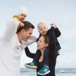 Junge Familie mit zwei kleinen Kindern bei einem liebevollen Outdoor-Fotoshooting am Meer – natürliche Familienfotos mit Emotionen