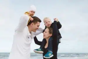 Emotionale Familienfotos Outdoor – unvergessliche Momente am Meer Junge Familie mit zwei kleinen Kindern bei einem liebevollen Outdoor-Fotoshooting am Meer – natürliche Familienfotos mit Emotionen