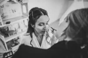 Braut beim Getting Ready – Make-up Artistin trägt Lidschatten auf.