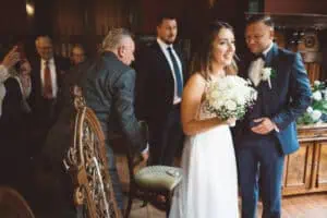 Brautpaar während der Trauung im Jagdschloss Gelbensande, umgeben von Hochzeitsgästen.