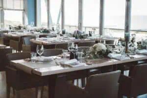 Stilvoll gedeckte Hochzeitstafel mit Blumenschmuck in der Blauen Boje mit Meerblick im Hintergrund.