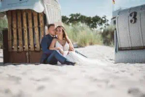 Brautpaar am Strand von Markgrafenheide sitzend vor einem Strandkorb, in inniger Umarmung.