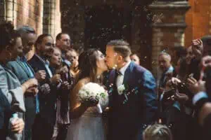 Kuss des Brautpaares beim Auszug aus dem Jagdschloss Gelbensande, umgeben von Gästen und Seifenblasen.