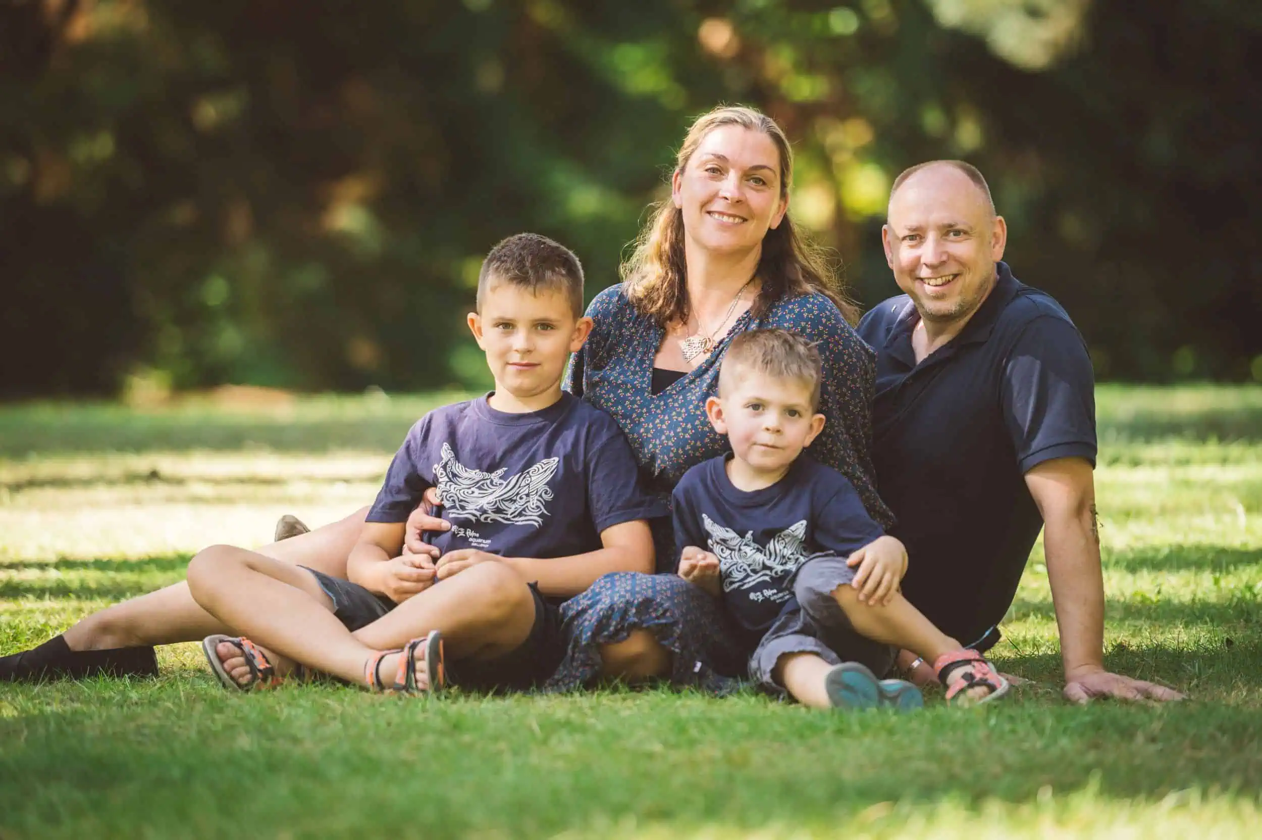 Familie im Botanischen Garten Rostock, entspannt auf dem Rasen sitzend. Eine Familie mit zwei Kindern, die auf dem Rasen im Botanischen Garten Rostock sitzt, glücklich und entspannt.