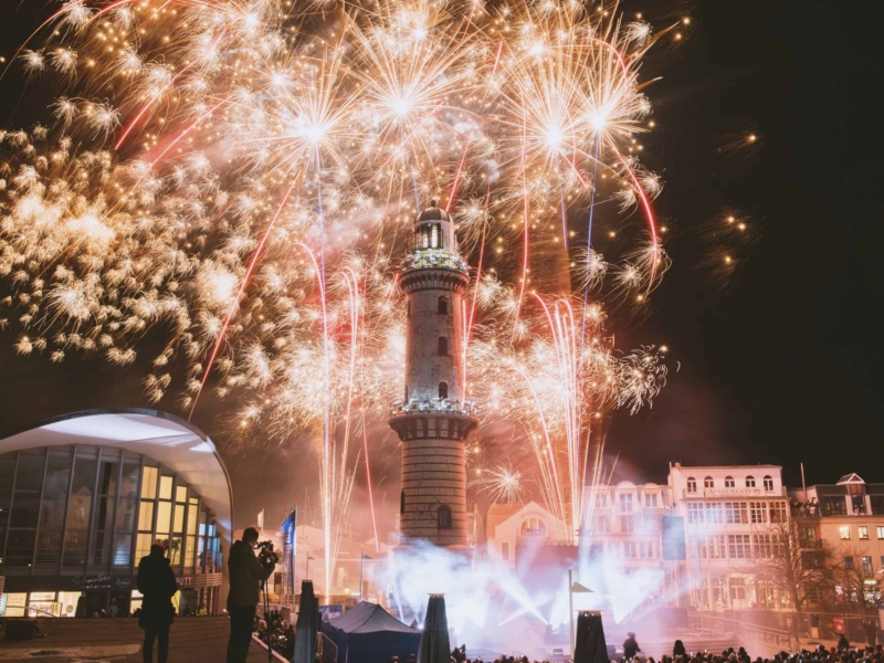 business-fotograf-event–rostock-067 Feuerwerk erleuchtet den Leuchtturm in Warnemünde beim Event Turmleuchten mit farbigen Feuerwerk am Nachthimmel.