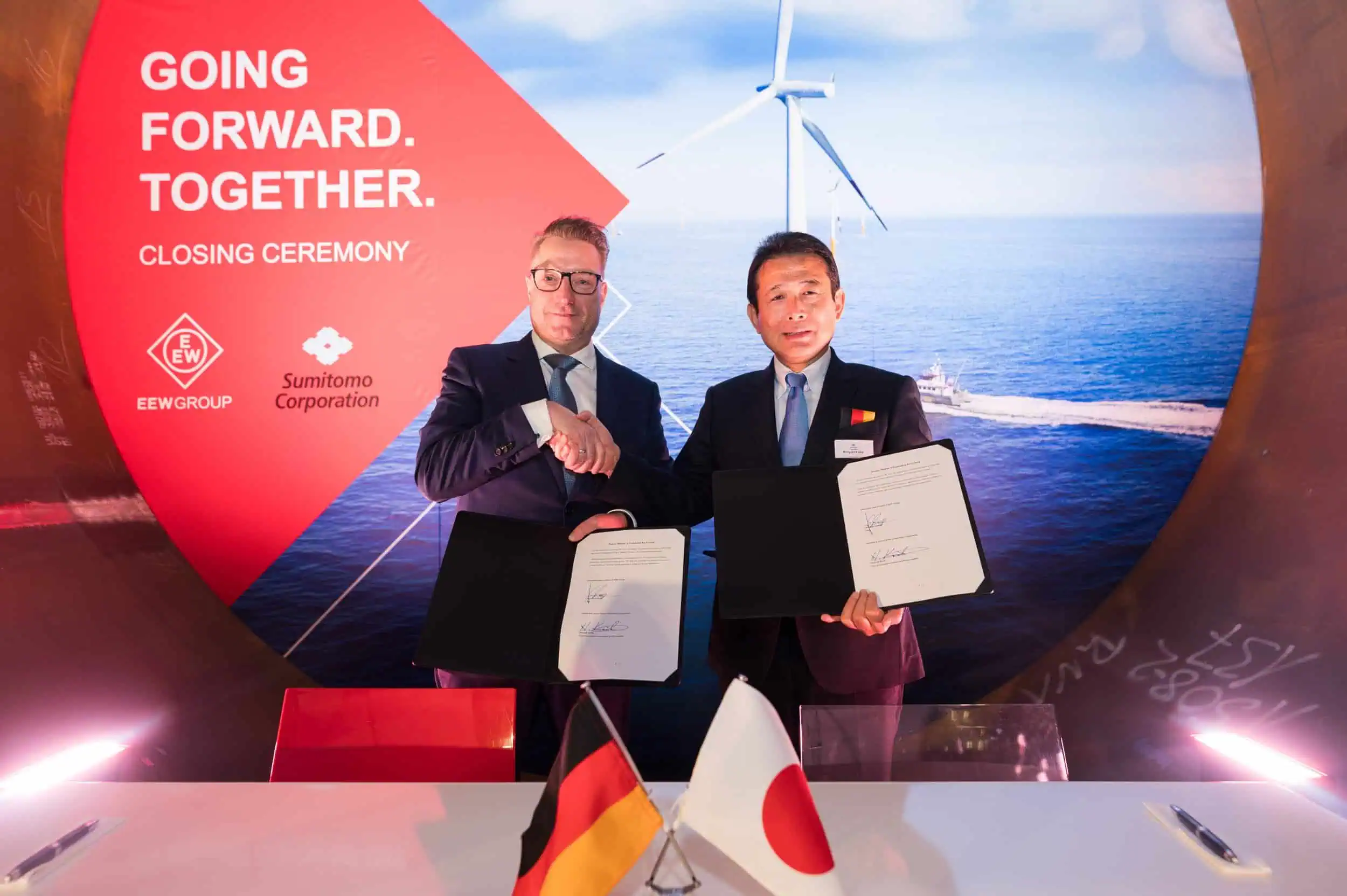 business-fotograf-event–rostock-134 Vertragsunterzeichnung zwischen Christoph Schorge von der EEW Group und Hiroyuki Koike von Sumitomo Corporation bei der Closing Ceremony vor einem Offshore-Windkraft-Motiv mit Deutschland- und Japan-Flagge.