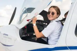 Junge Pilotin in Uniform sitzt lächelnd im Cockpit eines Trainingsflugzeugs der Lufthansa Aviation Training, fotografiert vom Rostocker Fotografen Martin Börner.