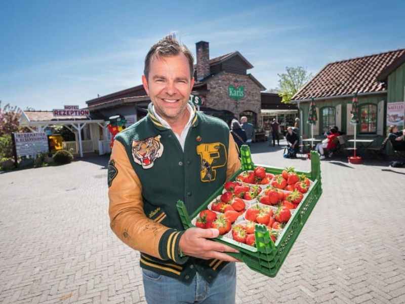Robert Dahl mit frischen Erdbeeren Robert Dahl hält frische Erdbeeren vor dem Eingang von Karls Erlebnis-Dorf in Rövershagen.