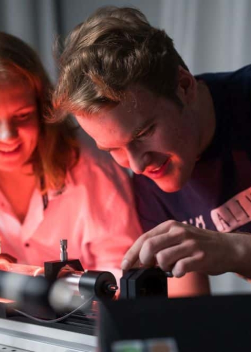 Zwei Studenten der physikalischen Fakultät der Uni Rostock bei einem Versuchsaufbau Ein Mitarbeiter und eine Mitarbeiterin der Uni Rostock arbeiten freudig an einer Maschine.