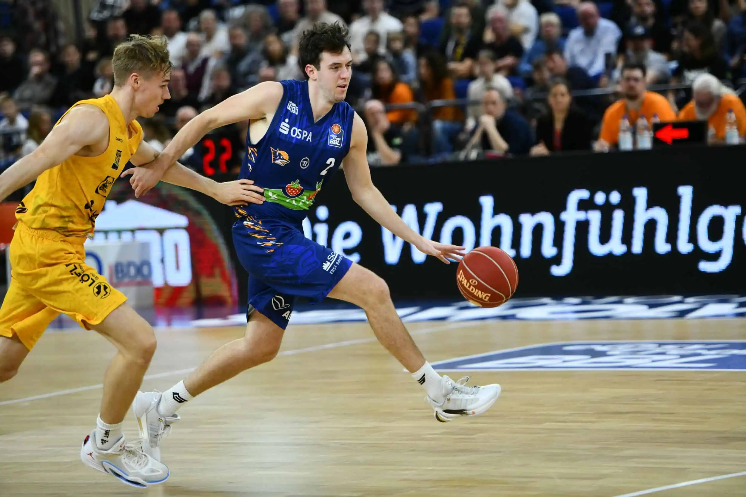 event-basketballspiel-rostocker-seawolves-tübingen-stadthalle-023 Tyler Nelson von den Rostock Seawolves im blauen Trikot beim Dribbling im Spiel gegen seinen Gegenspieler.