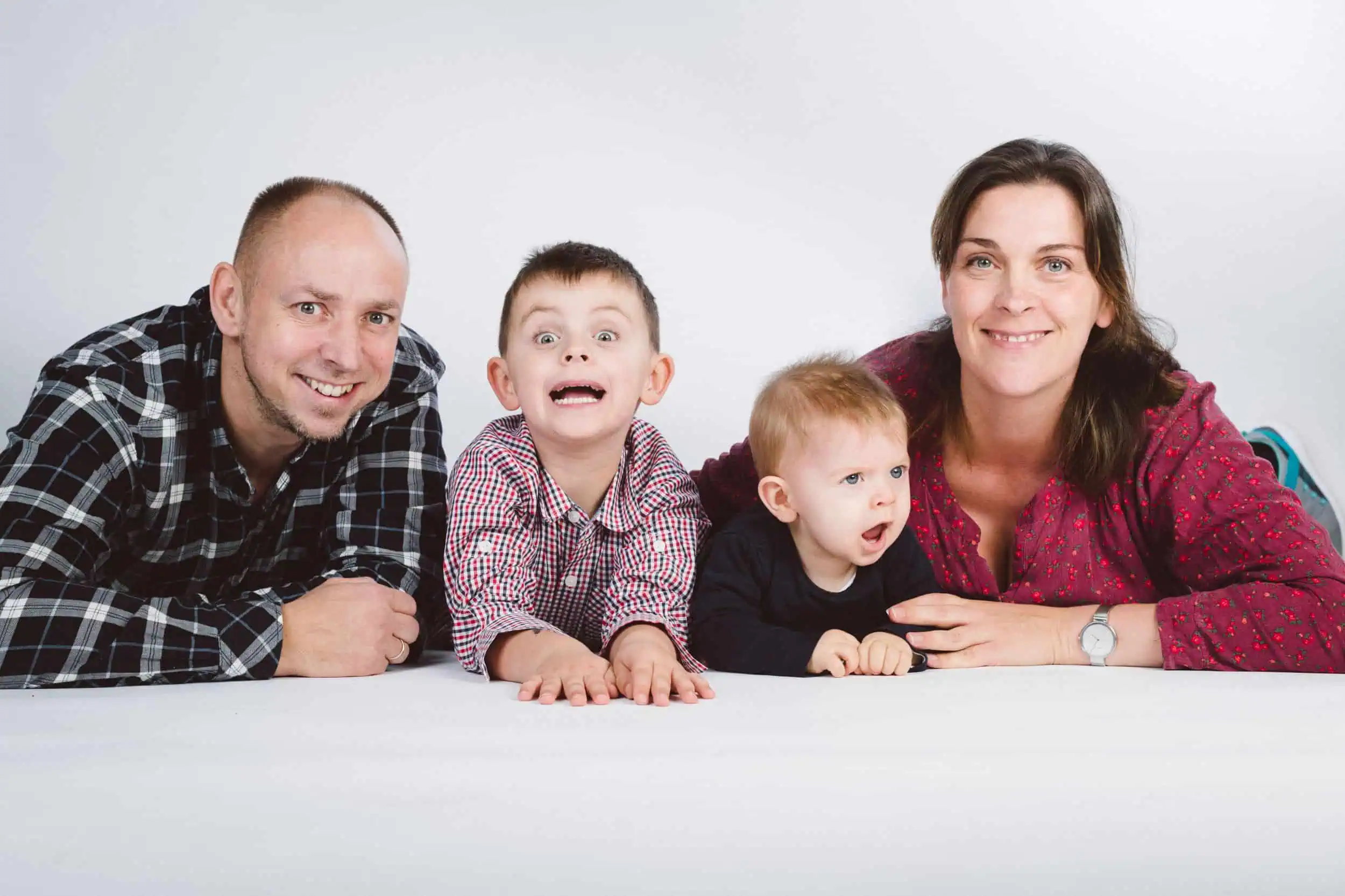 Preise für ein Fotoshooting im Rostocker Fotostudio Fröhliche Familie mit zwei Kindern posiert spielerisch im Fotostudio auf weißem Hintergrund.