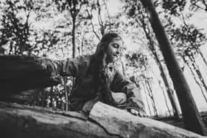 Schwarz-weiß-Foto eines Mädchens, das im Gespensterwald Nienhagen über Baumstämme klettert und konzentriert nach oben schaut.