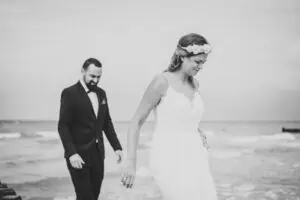 Brautpaar barfuß am Ostseestrand bei Ahrenshoop – natürliche Schwarz-Weiß-Aufnahme einer intimen Hochzeit zu zweit mit Brautkleid und Anzug.