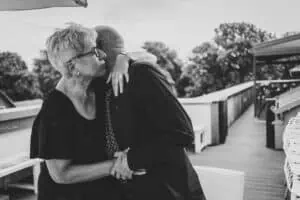 Älteres Paar in liebevoller Umarmung nach einer intimen Trauung zu zweit am Ostseestrand, emotionale Schwarz-Weiß-Aufnahme mit Fokus auf Nähe und Verbundenheit.