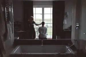 Hochzeitsgast oder Bräutigam wird in einem Hotelzimmer in Ahrenshoop am Fenster frisiert – stimmungsvolles Getting-Ready-Bild mit Blick ins Grüne.