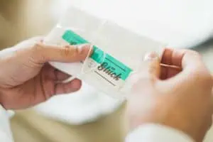 Nahaufnahme von Händen, die ein sorgfältig gefaltetes Stofftaschentuch mit einer Schleife und einem Etikett mit dem Wort "Glück" in der Hand halten – Hochzeitsvorbereitungen.