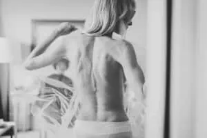 Rückansicht einer Braut beim Getting Ready, umhüllt von zartem Tüll in Schwarz-Weiß – emotionaler Moment vor der Hochzeit.