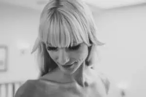 Zartes Schwarz-Weiß-Porträt einer nach unten blickenden Braut mit Ponyfrisur und natürlichem Ausdruck.