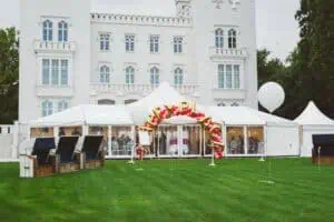 Weiße Hochzeitszelte mit großer Ballongirlande vor dem eleganten Grand Hotel Heiligendamm, ergänzt durch Strandkörbe und große Luftballons auf der gepflegten Rasenfläche – festliche Outdoor-Hochzeitslocation an der Ostsee.