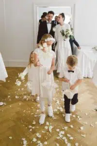 Frisch verheiratetes Brautpaar verlässt den Trausaal im Grand Hotel Heiligendamm, begleitet von Blumenmädchen und einem Jungen, die weiße Blütenblätter streuen.