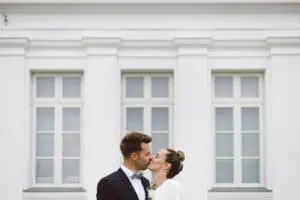 Brautpaar küsst sich innig vor der weißen klassizistischen Fassade des Grand Hotel Heiligendamm.