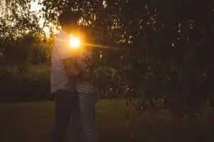 Verliebtes Paar umarmt sich bei Sonnenuntergang unter einem Baum, während des Paar-Fotoshooting