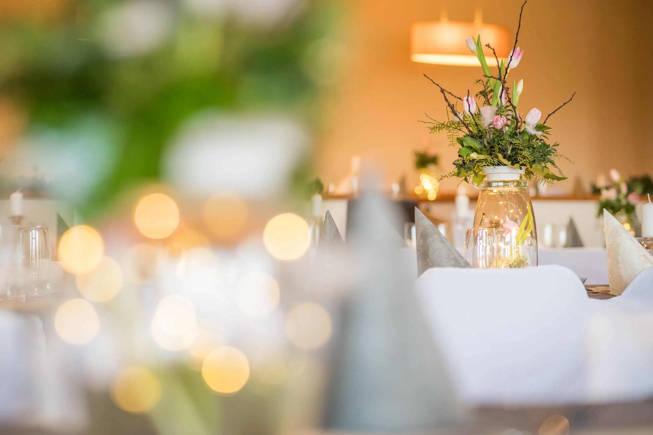 Martin Boerner Festlich gedeckter Tisch im Restaurant zur Kegelbahn in Lübow mit stilvoller Blumendekoration in Glasvase und stimmungsvollem Kerzenlicht.