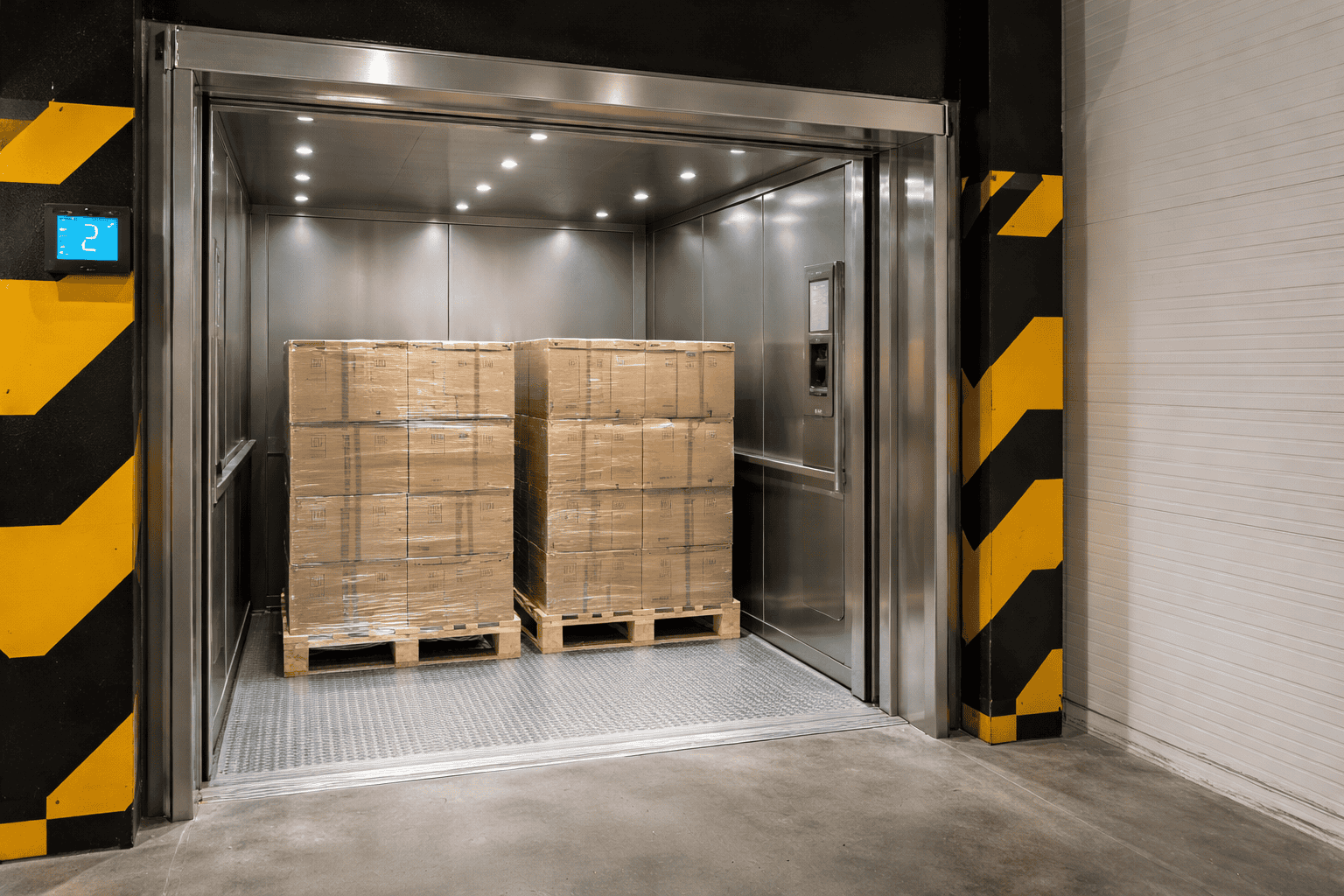 elevador de carga industrial transportando dois paletes em cabine metálica para movimentação vertical de cargas em galpão logístico