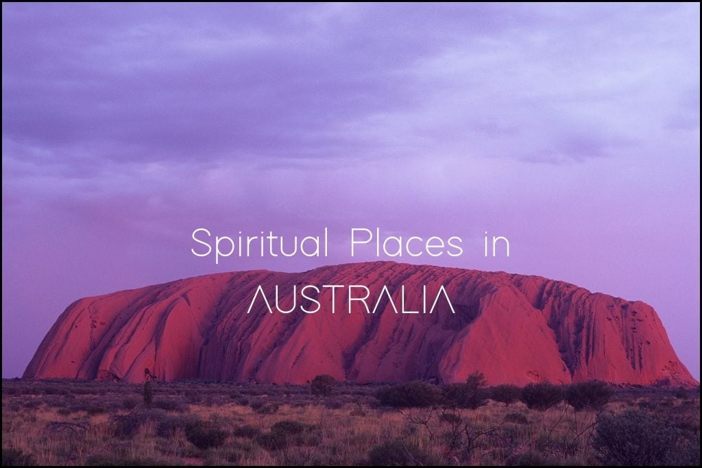 Uluru, also known as Ayers Rock, is shown at dusk with its iconic red sandstone glowing under the purple twilight sky. The image is labeled 'Spiritual Places in AUSTRALIA,' indicating the blog post may explore spiritually significant locations within Australia.