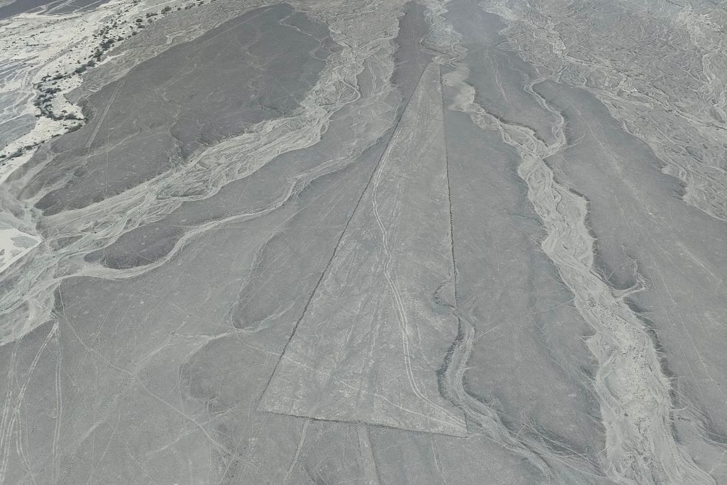 Why are the Lines of Nazca a Mystery of Peru? Aerial view of the Nazca Lines in Peru, showcasing the intricate geoglyphs etched into the desert sands, with a focus on the straight lines intersecting natural formations. Lines of Nazca.
