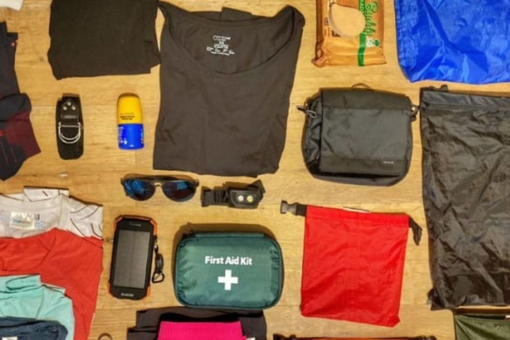 How to Get to the Lost City Colombia? My Personal Experience in 2026! A variety of trekking gear laid out on a surface, including clothing, a first aid kit, water bottles, a small backpack, sunglasses, and other essential items, organized neatly for packing.