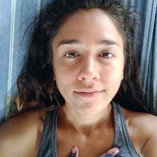 How to Get to the Lost City Colombia? My Personal Experience in 2026! A young woman with long dark hair is lying on a striped surface, looking directly at the camera with a neutral expression. She is wearing a dark tank top.
