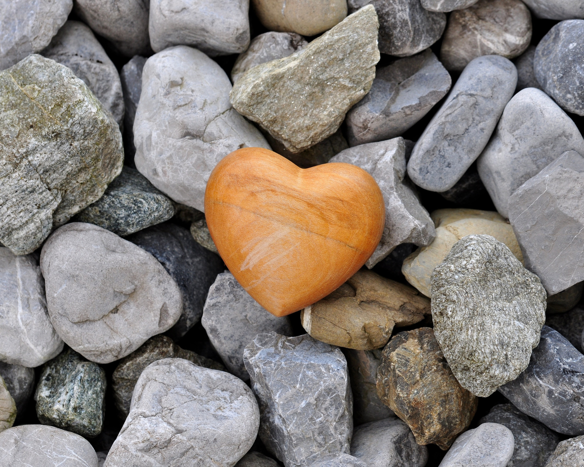 Anahata Chakra Meaning: All About the Heart Chakra Powers Wooden heart placed among gray stones, representing emotional grounding, resilience, and heart-centered healing.